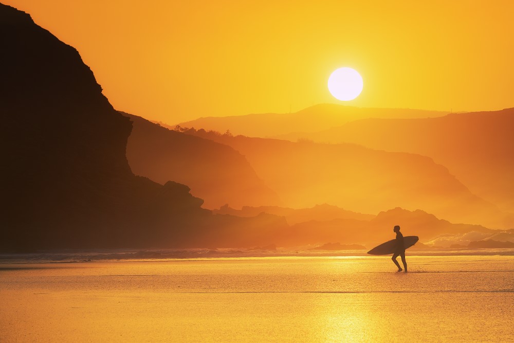sunset lone surfer exiting the water mountains beautiful nature
